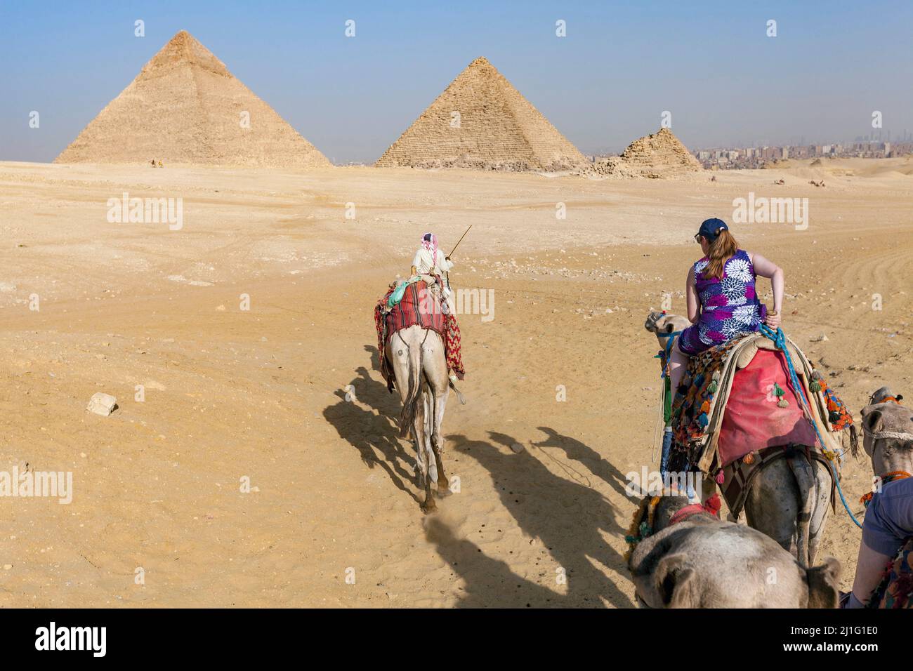 Tourists riding camels near the pyramids of Egypt Stock Photo