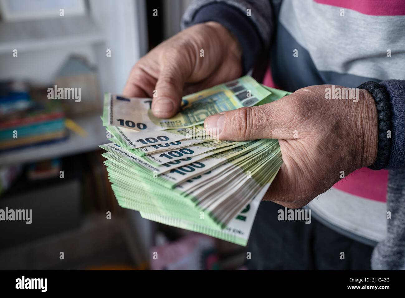 Close up on hands of unknown caucasian senior man holding and counting 100 euro banknotes money wealth insurance payment or lifetime savings copy spac Stock Photo
