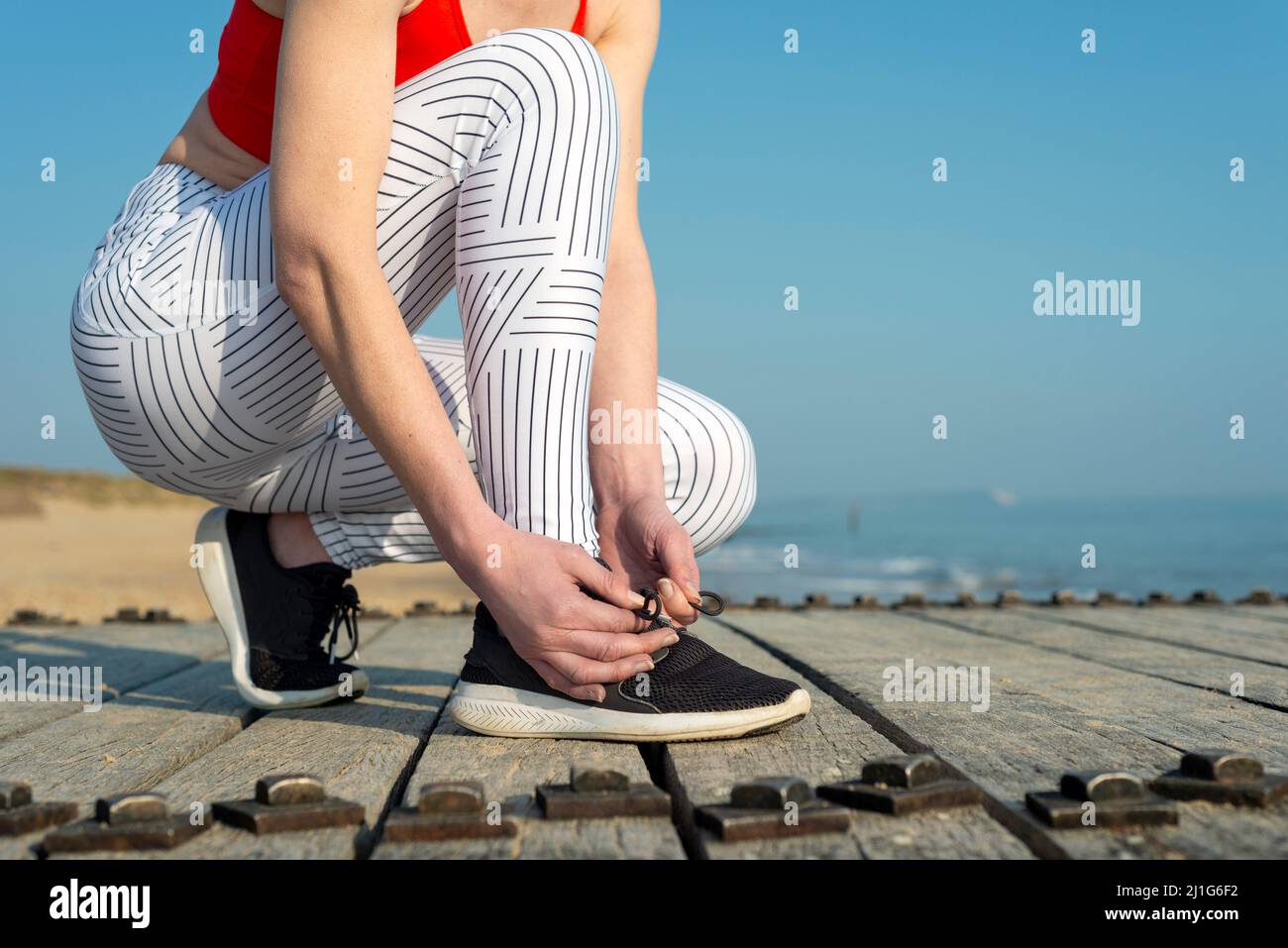 Female runner tying her shoes preparing for a run a jog outside Stock Photo