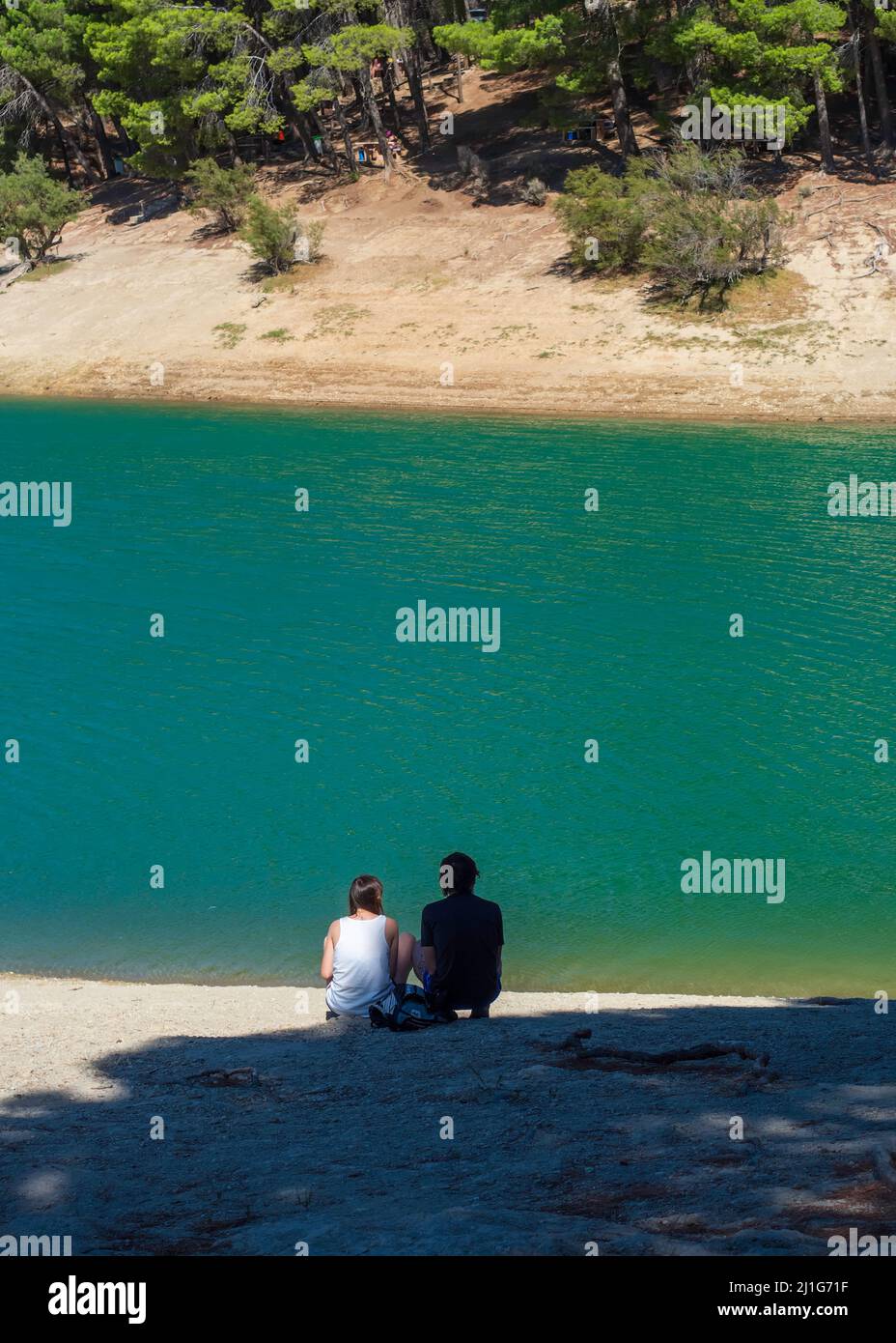 Heterosexual couple sitting on the shore of El Chorro reservoir in Malaga. Stock Photo