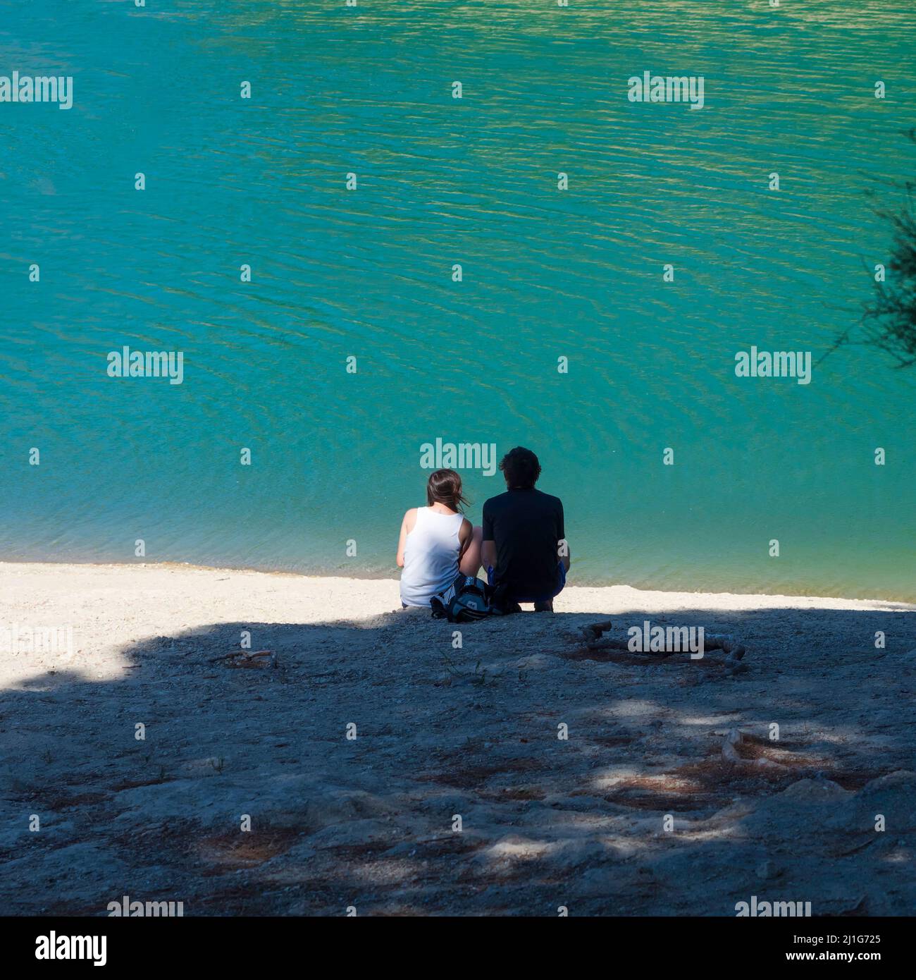 Heterosexual couple sitting on the shore of El Chorro reservoir in Malaga. Stock Photo