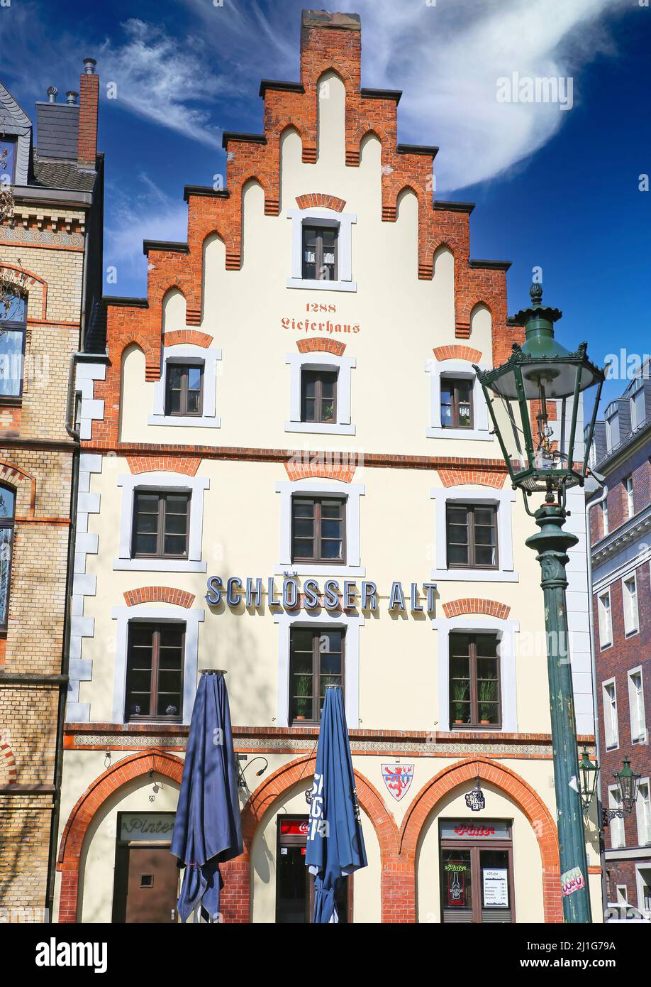 Düsseldorf, Germany - March 23. 2022: View on historic old building with gabled roof against blue sky, logo of local traditional Schlösser Alt brewery Stock Photo