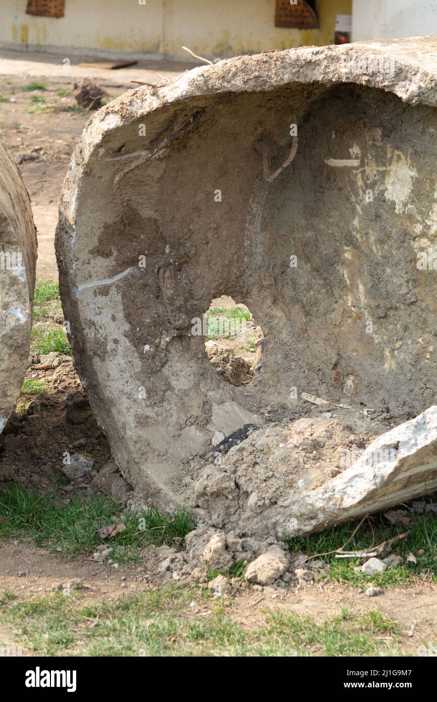 Sewer ring. Broken sewer ring covered with clay and sand on the lawn near the playground. Construction or repair of sewerage of a residential apartmen Stock Photo