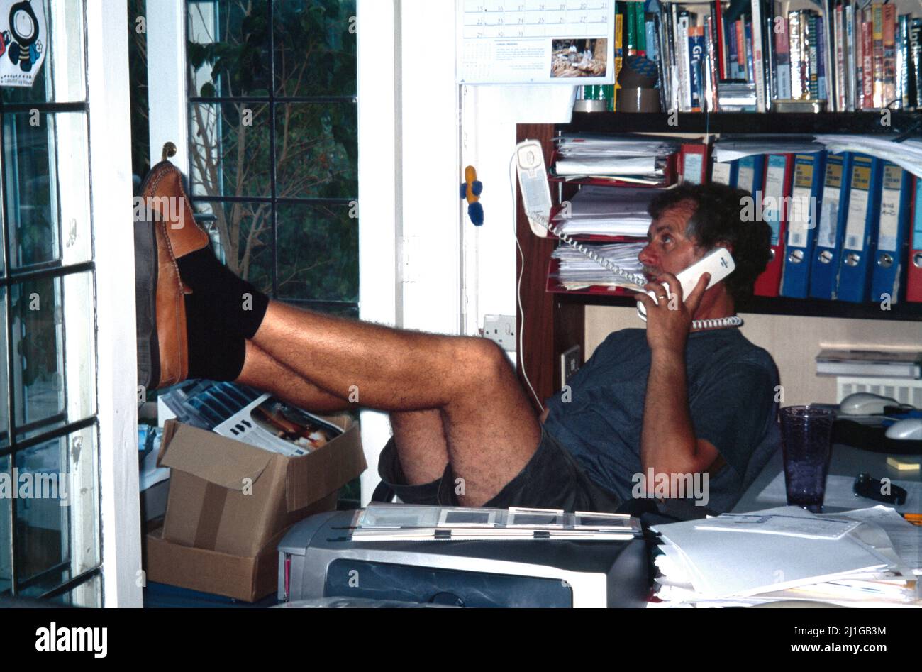 Man Working in Home Office Relaxed With Feet up Talking on The Telephone Stock Photo