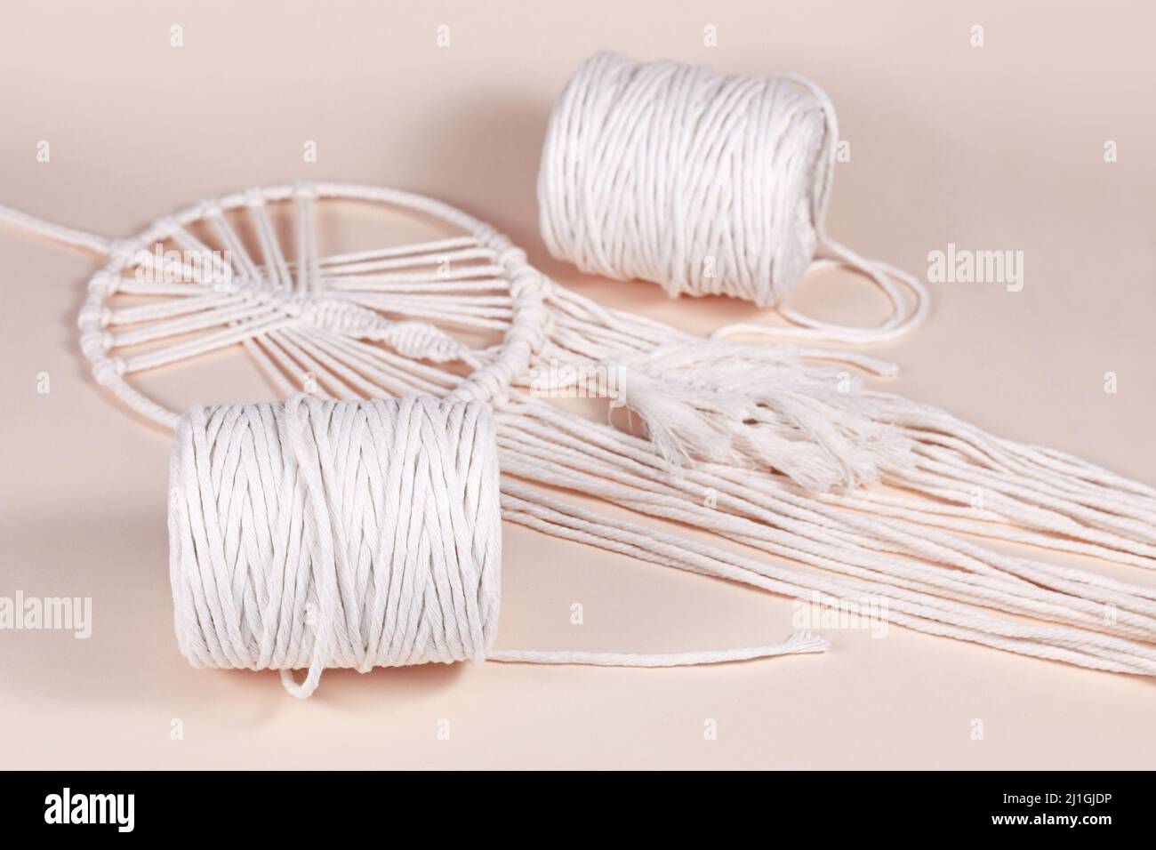 Cream white cotton macrame cord used for DIY decoration object on beige background Stock Photo