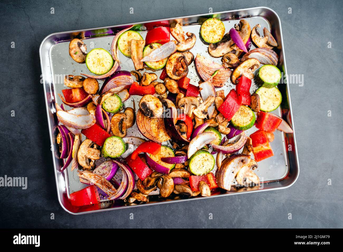 Overhead View of Raw Vegetables Seasoned with Olive Oil and Spices: Sliced and seasoned vegetables on a sheet pan Stock Photo