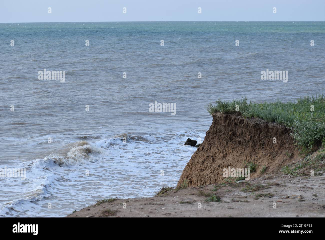 Sea cliffs of boulder clay in front of beaches. Clay Cliffs and Beach with Blue Sky and Water. Precipice coast near the sea. Visiting stunning sandy b Stock Photo