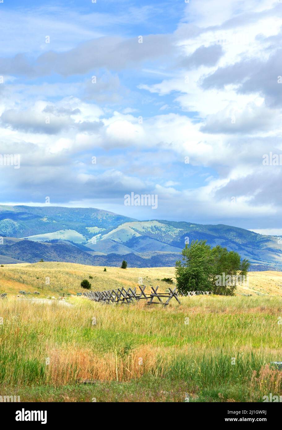 Meadow in Happy Valley, Wyoming has view of the Absaroka Mountains.  Rustic wooden fence points the way. Stock Photo