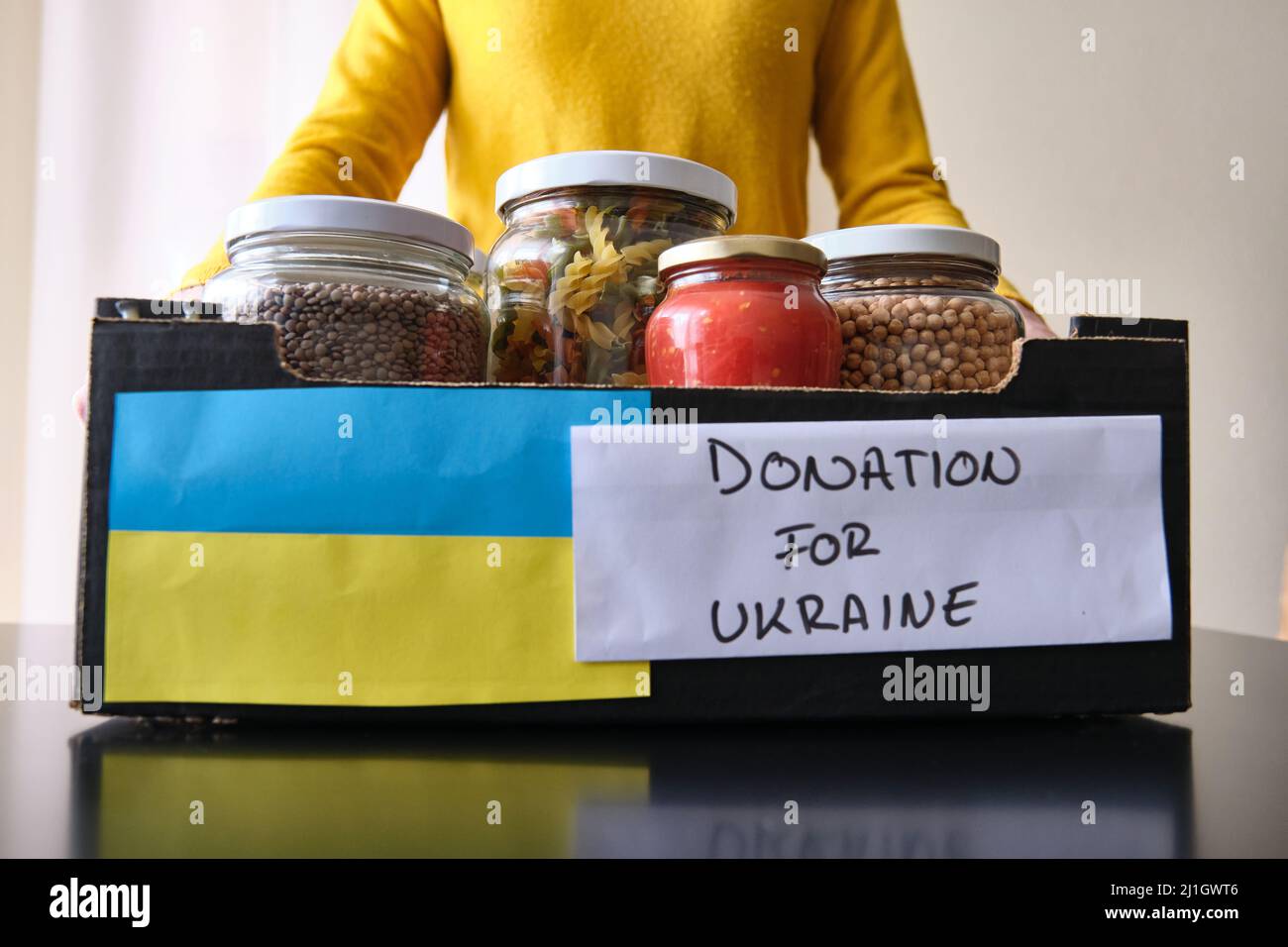 A Unrecognizable woman picking up a box of food to donate to Ukrainian