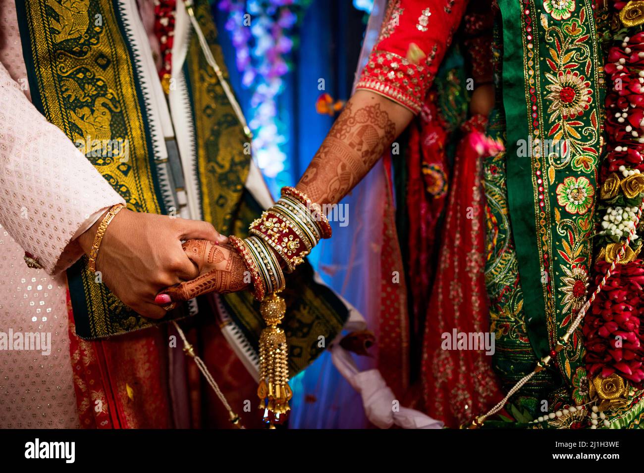 A closeup shot of an Indian couple with hands holding each other in traditional dresses Stock Photo