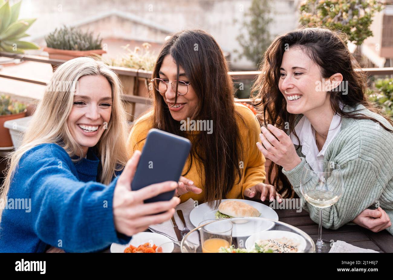 Multiracial Happy Friends Having Fun Taking Selfie With Mobile Phone At Vegan Restaurant Outdoor 