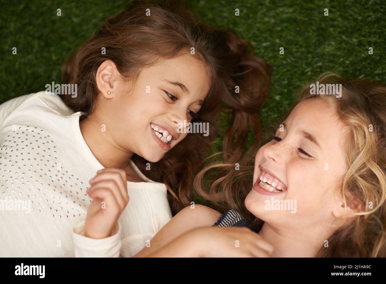 Pure childhood delight. Cropped shot of two little girls lying on their backs outside. Stock Photo
