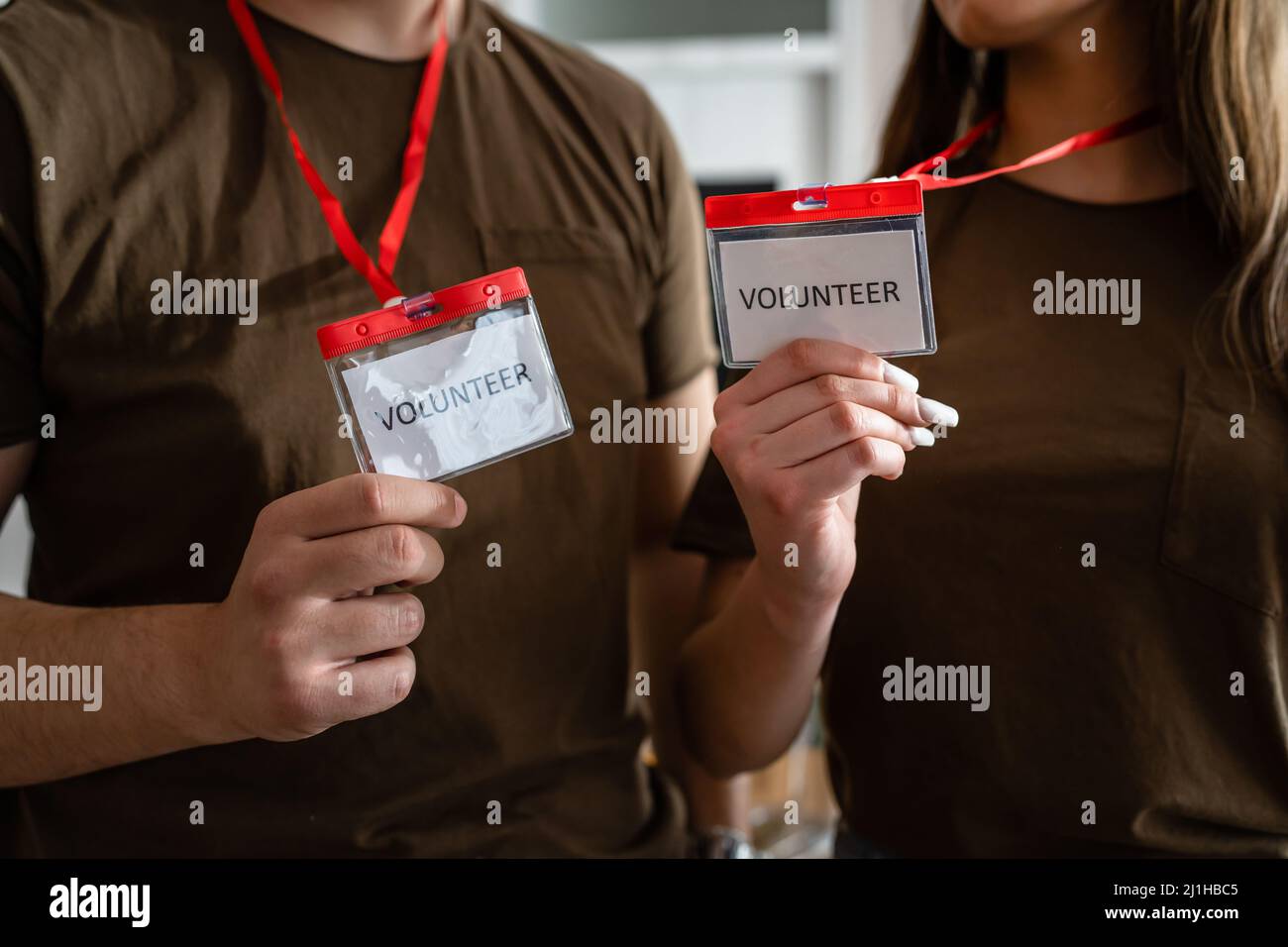 Close up on hands of two unknown man and woman holding id cards with volunteer title working at charity foundation copy space humanitarian aid concept Stock Photo