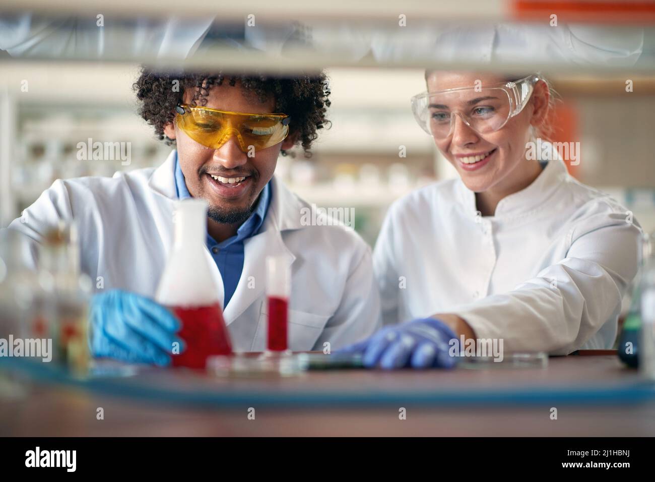 Young chemistry students in a protective gear like working with colorful chemicals in a relaxed atmosphere in the university laboratory. Science, chem Stock Photo