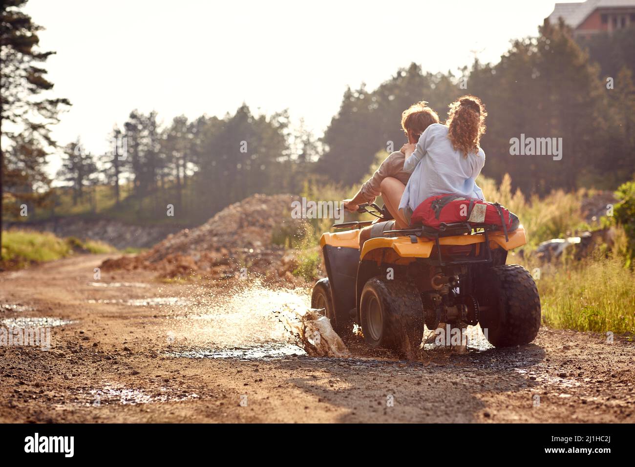 Young couple on an off road adventure. Man driving quad with girlfriend sitting behind him, and enjoying the ride in mountains forest. Nature outdoors Stock Photo