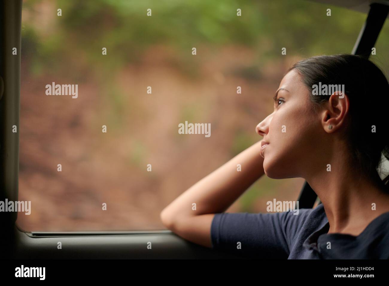 A long journey ahead. A beautiful woman looking out of a car window. Stock Photo