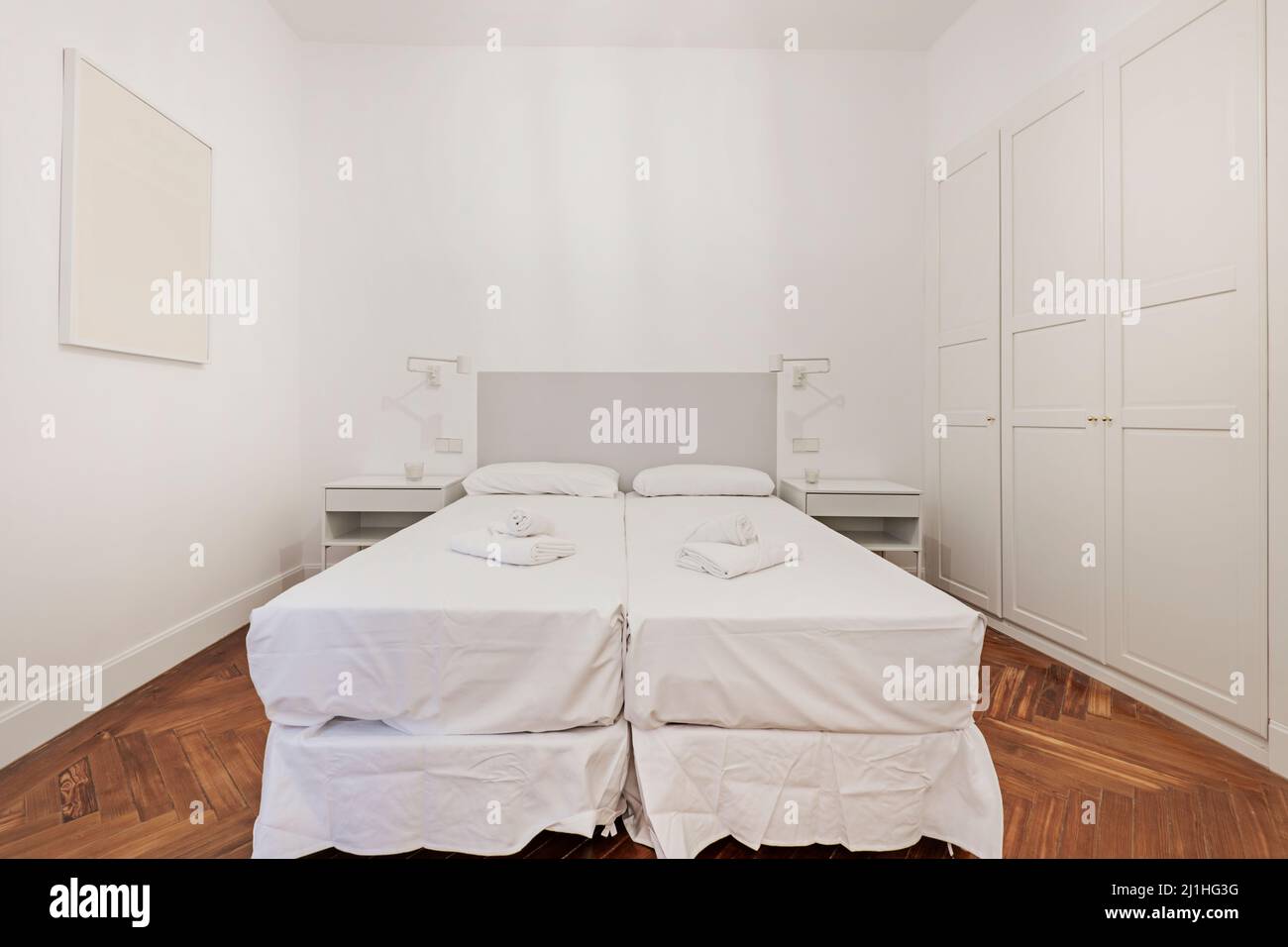 Bedroom with double beds and white sheets, bath towels on the beds and