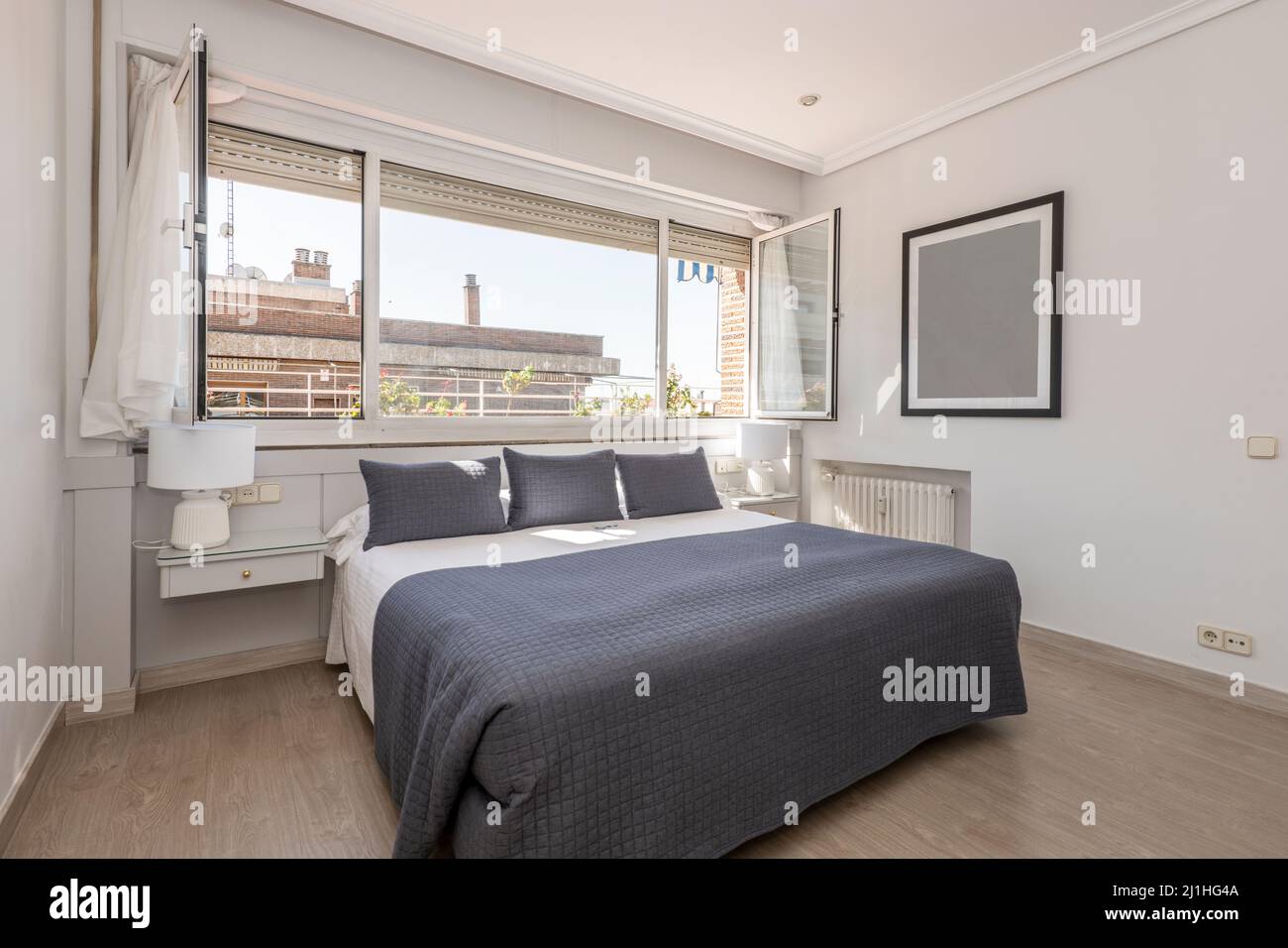 Bedroom with a double bed and white sheets, blue cushions and a