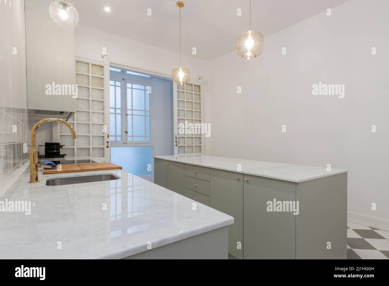 Kitchen with long white marble countertops with sink and glazed wooden