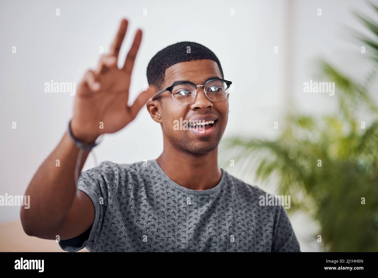 Hey, wait up. Shot of a young businessman raising his hand in an office