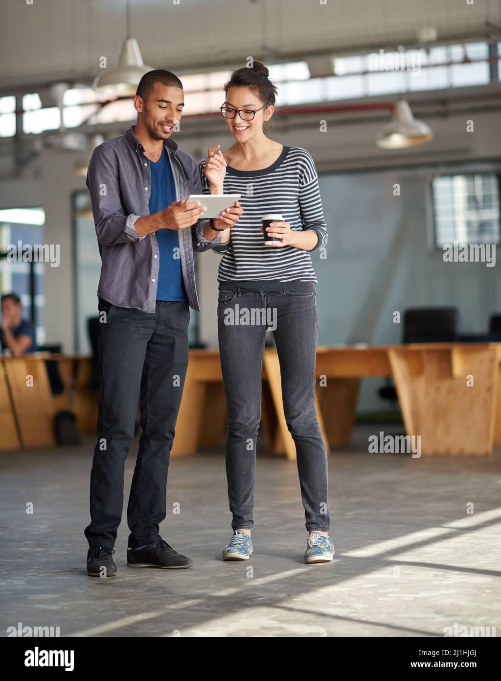 Sharing the industry developments. Young woman seeing something entertaining on her colleagues digital tablet. Stock Photo
