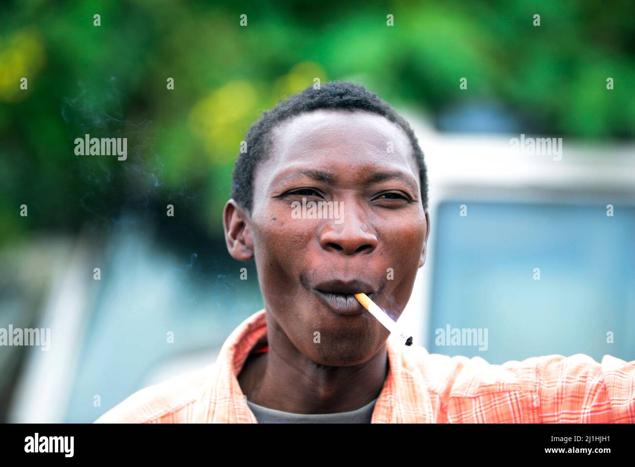 A Tanzanian man smoking his cigarette. Stock Photo