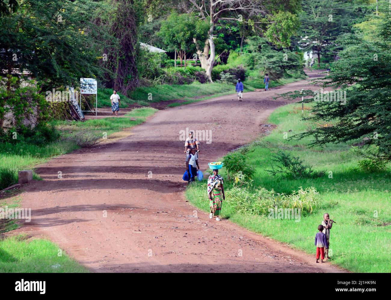 Locals walking on the unpaved road at Mto Wa Mbu, Tanzania. Stock Photo