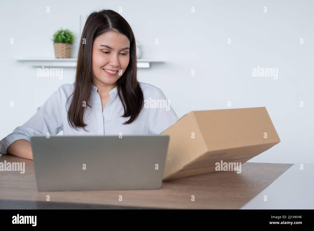 Happy young Asian woman entrepreneur, Hold package and Smile for sale success of online shopping store at home office, Concept of merchant, small busi Stock Photo