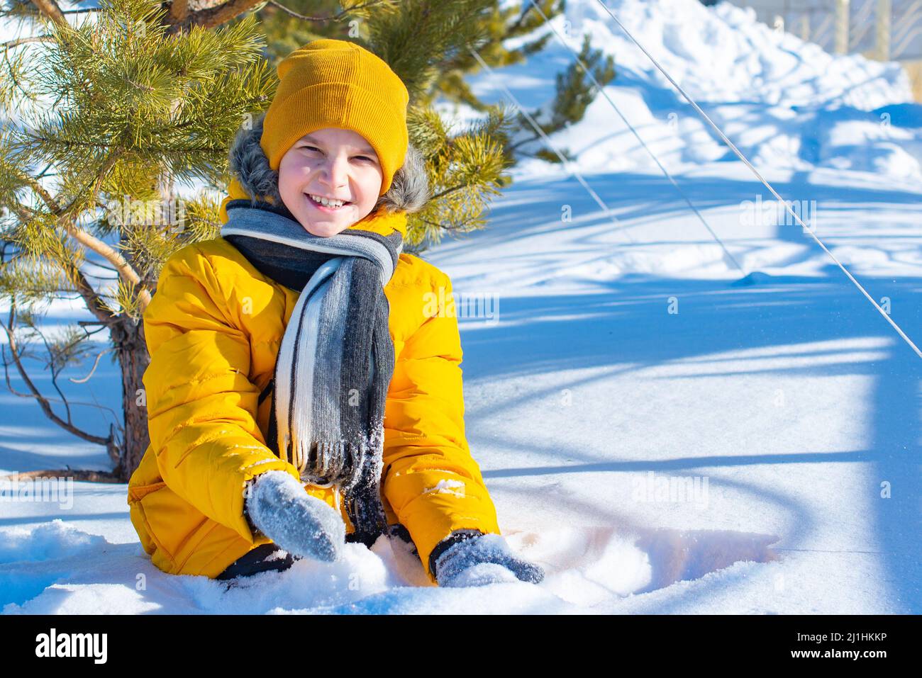 one boy in a yellow jacket in the snow Stock Photo