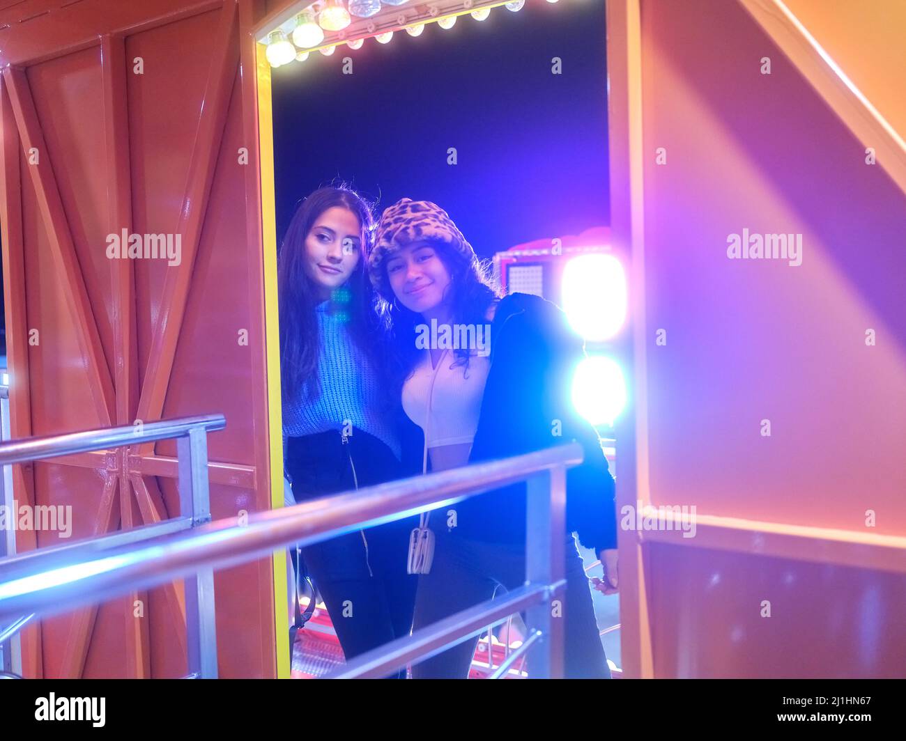 Friends waiting on the entrance of a attraction of a night fair Stock ...