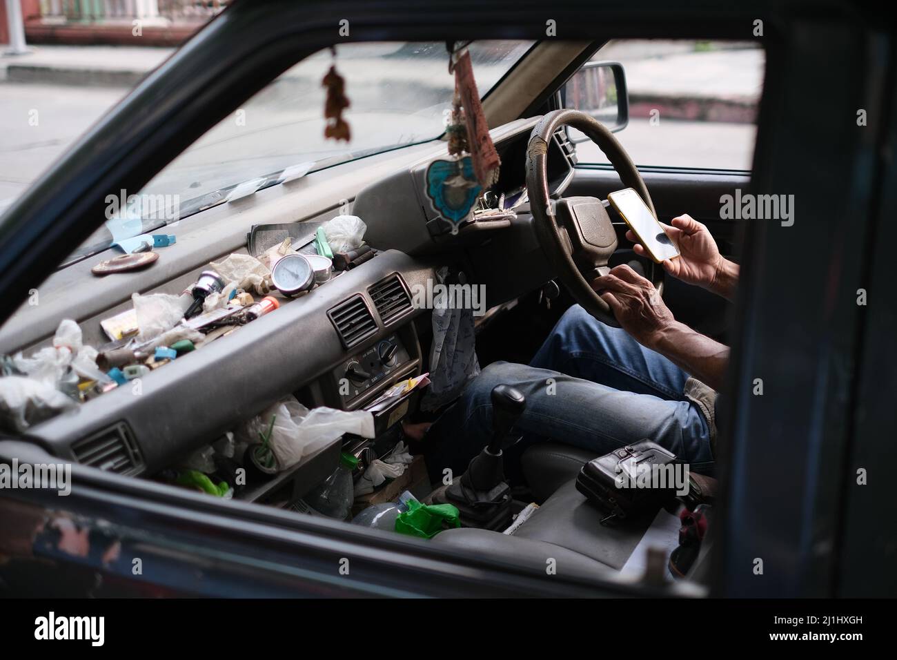 Overworked hands of an elder man on a steering wheel and the interior ...