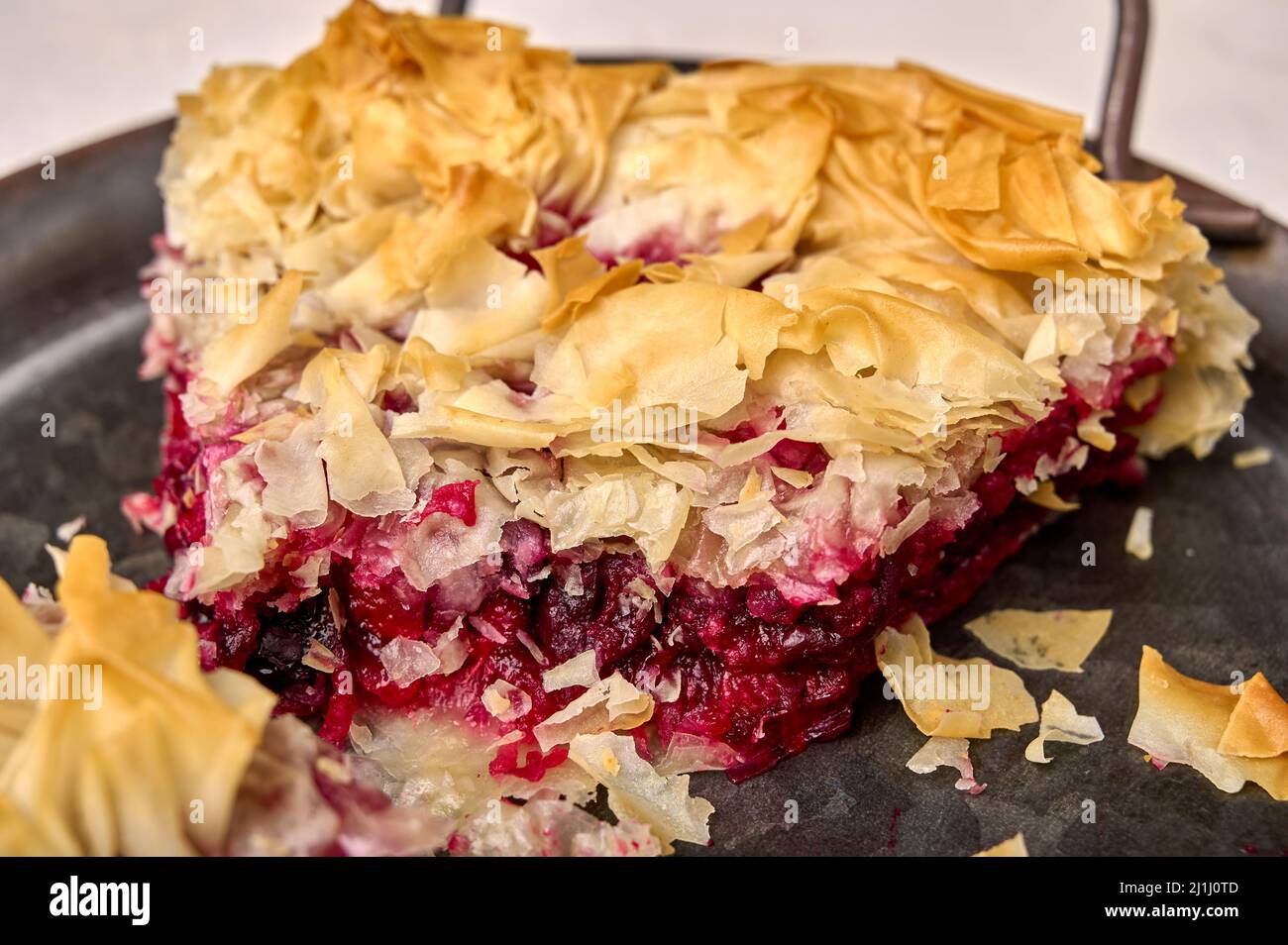 Piece of homemade cherry pie from filo dough with a view of the filling. Selective focus, close up Stock Photo