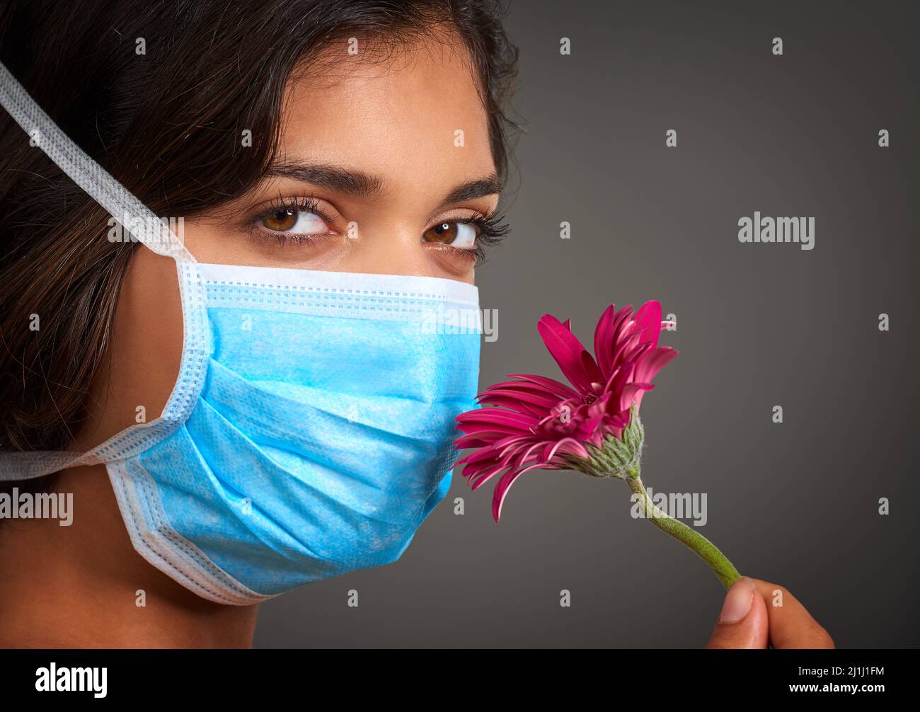 I cant seem to smell anything. Closeup of a young woman with a doctors mask on looking at the