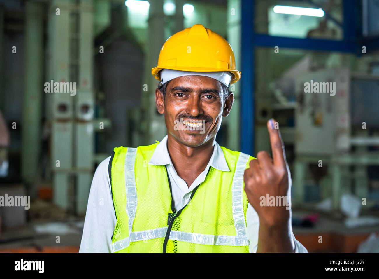 industrial worker showing Ink marked finger after voting at electionby looking at camera - concept of responsibility, freedom and democracy. Stock Photo