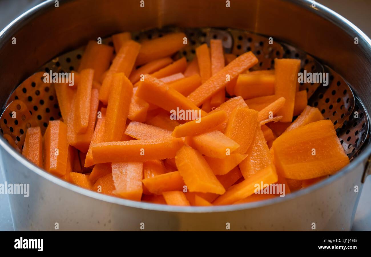A pot of bright orange chopped carrots ready to be steamed Stock Photo