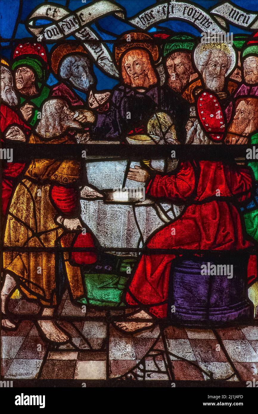The Last Supper, with disciple Judas Iscariot shown clutching his reward for betrayal, a red bag holding 30 pieces of silver.  Detail of vivid Renaissance stained glass depicting scenes from the Passion of Christ in the Église Saint-Rémi at Ceffonds, a village in the Haute-Marne department of the Champagne region in northeast France. Stock Photo