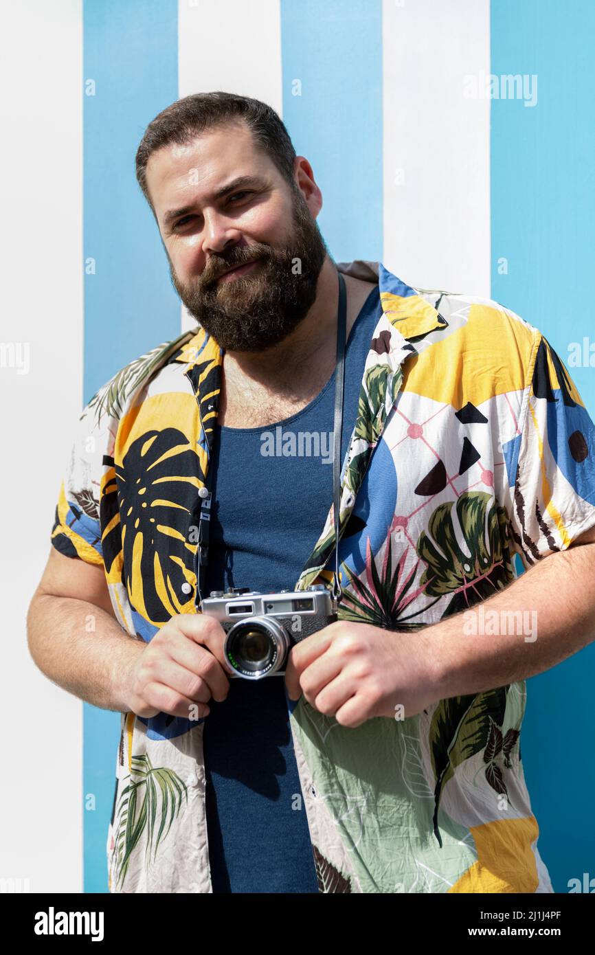 Portrait of big man with camera and summer clothes. Concept of tourism and vacation. Stock Photo