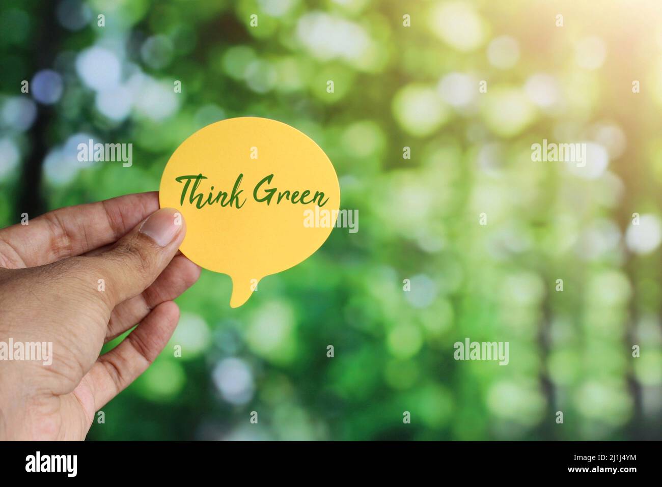 Hand holding speech bubble with text Think Green on bokeh background ...