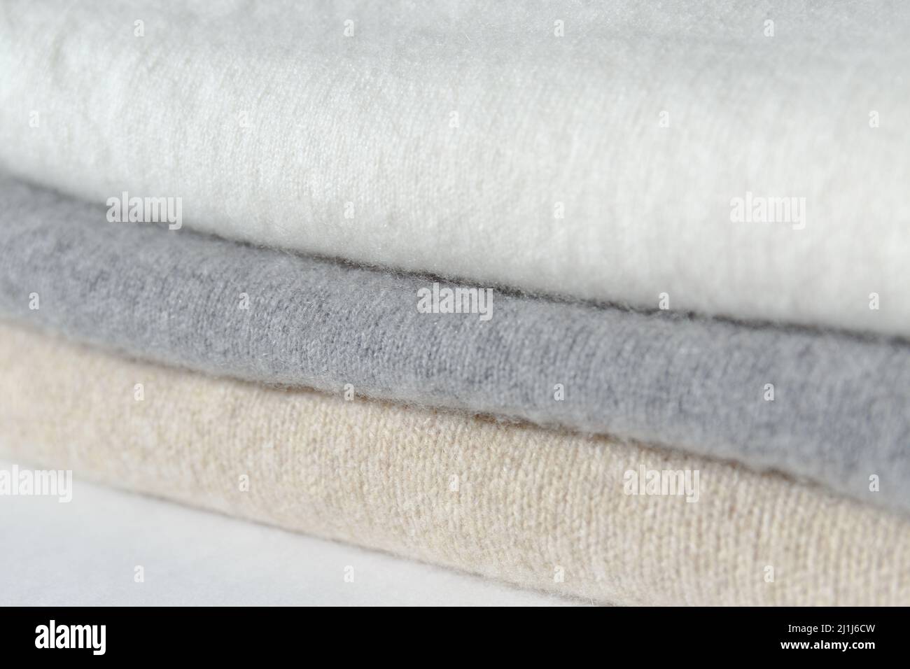 Cashmere clothing. The white, gray, and beige sweaters are stacked. Woolen things in pastel colors Stock Photo