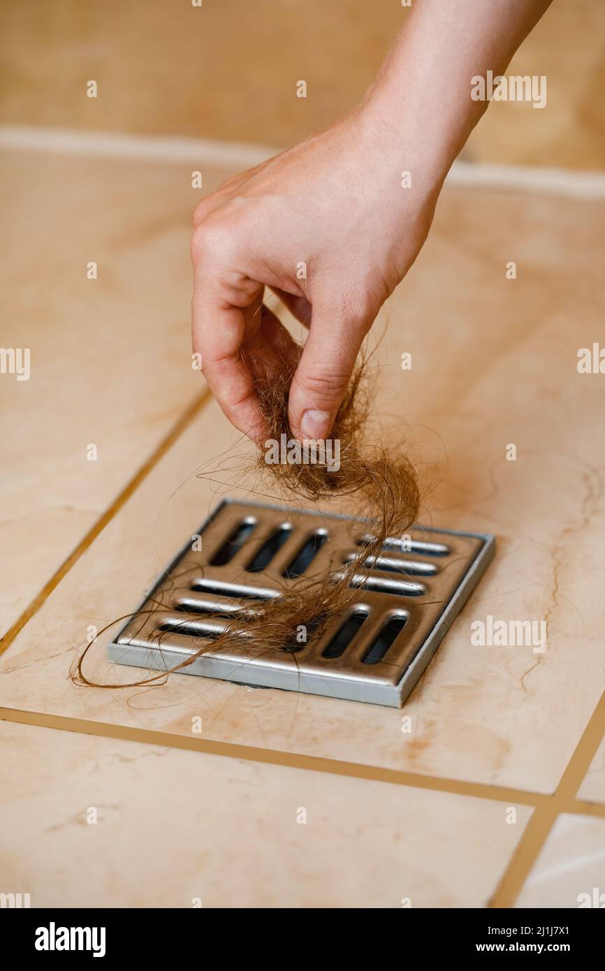 Woman removing hair clump from the shower drain Stock Photo Alamy