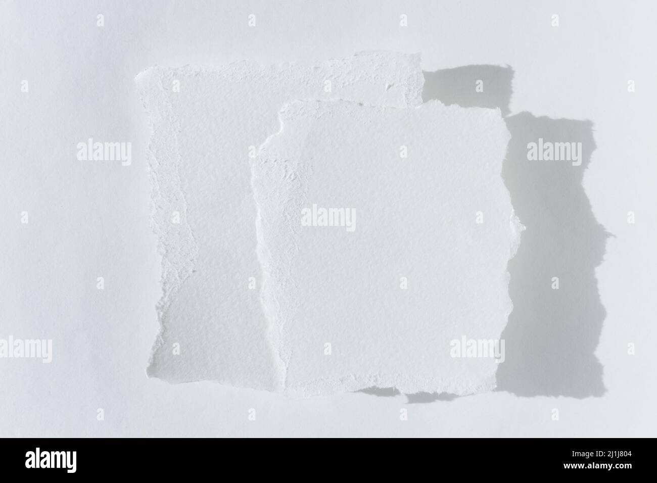A white torn note, scraps of paper. Two pieces of torn white paper on a light background. Stock Photo