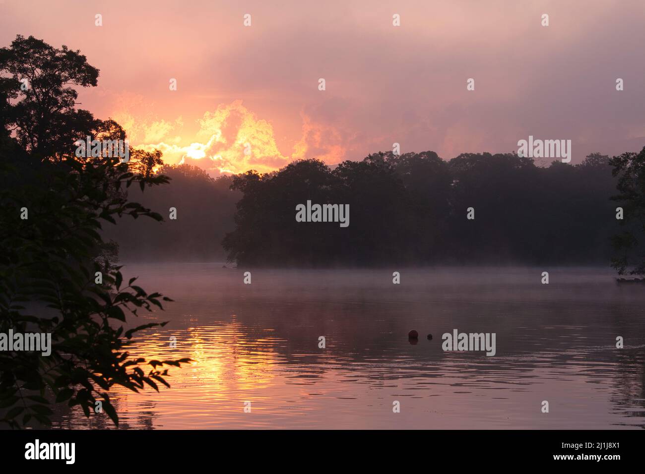 Explosive orange sunrise over a calm lake Stock Photo