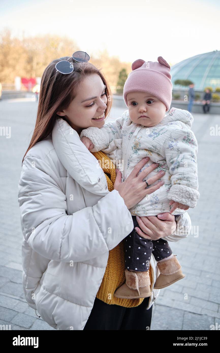Mother holding baby smiling to camera. Real life authentic casual mom looking to camera holding Stock Photo