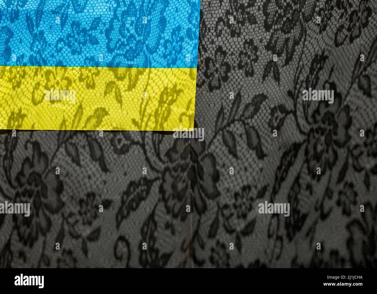 Blue and yellow flag on a black background with lace shadows. Colors of the Ukrainian flag. Place for text. Stand with Ukraine Stock Photo