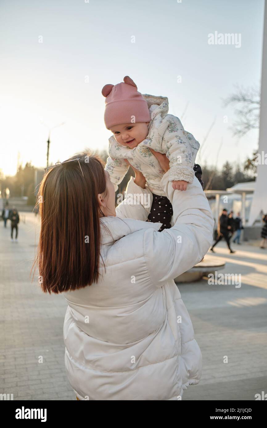 happy harmonious family outdoors. mother throws baby up, laughing and