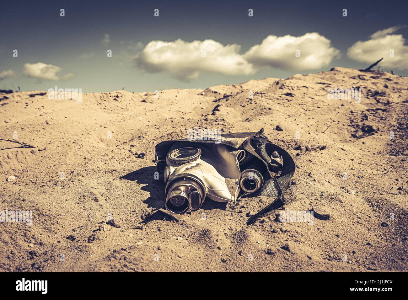 Military gas mask in the sunburned desert. Destroyed gas mask in a desert area. Stock Photo