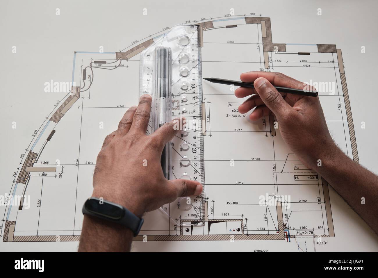 Close-up of Black hands drawing floor plan using pencil and engineering ruler Stock Photo