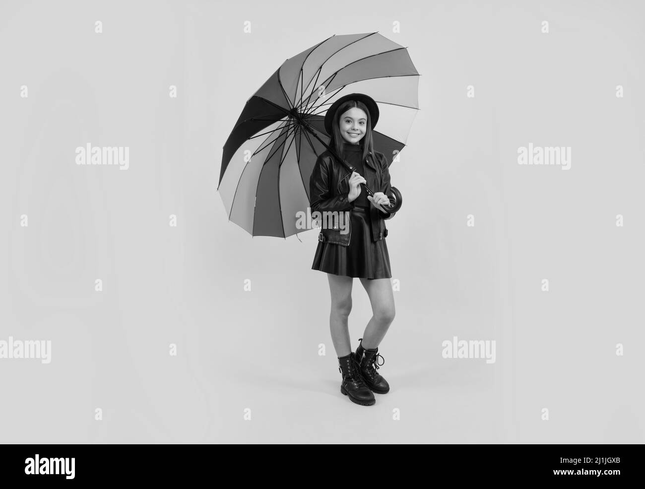happy teen girl in hat and leather clothes under rainbow umbrella, autumn rain Stock Photo
