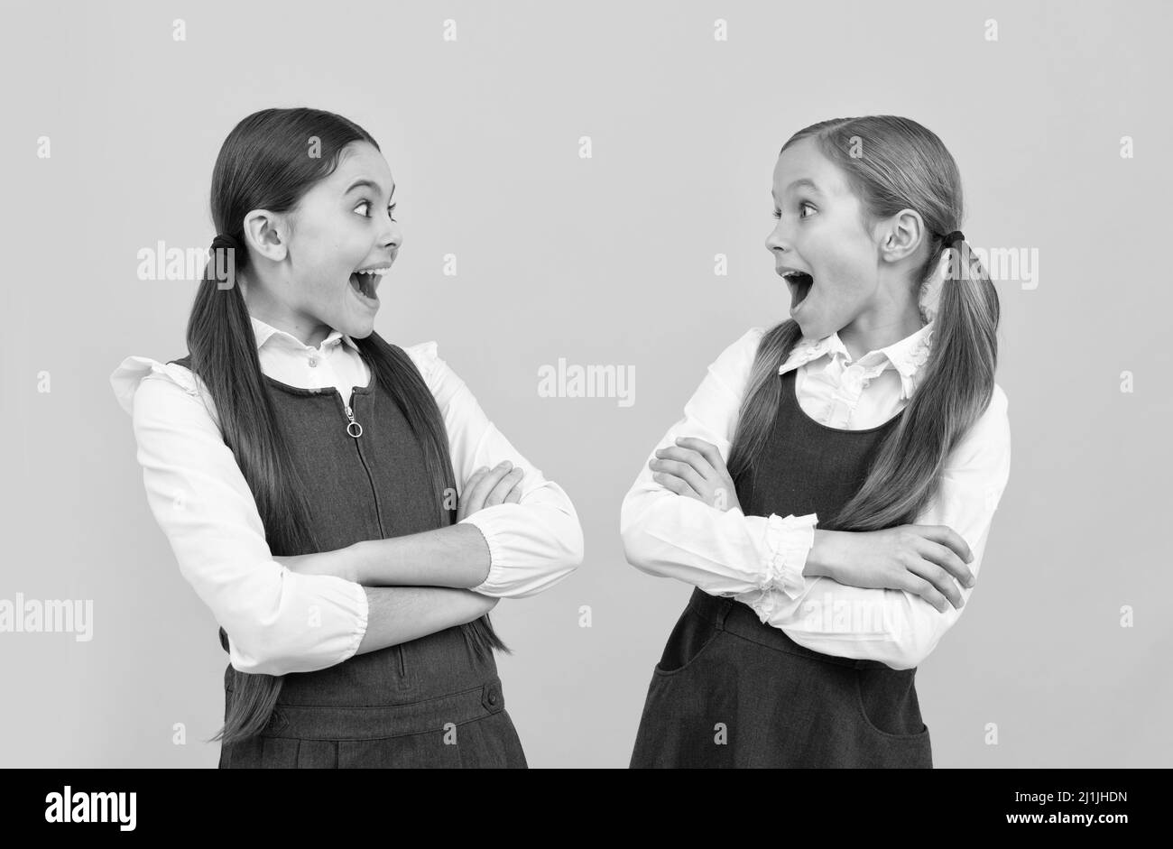 Surprised little kids look at each other with open mouths in formal school uniforms, surprise Stock Photo