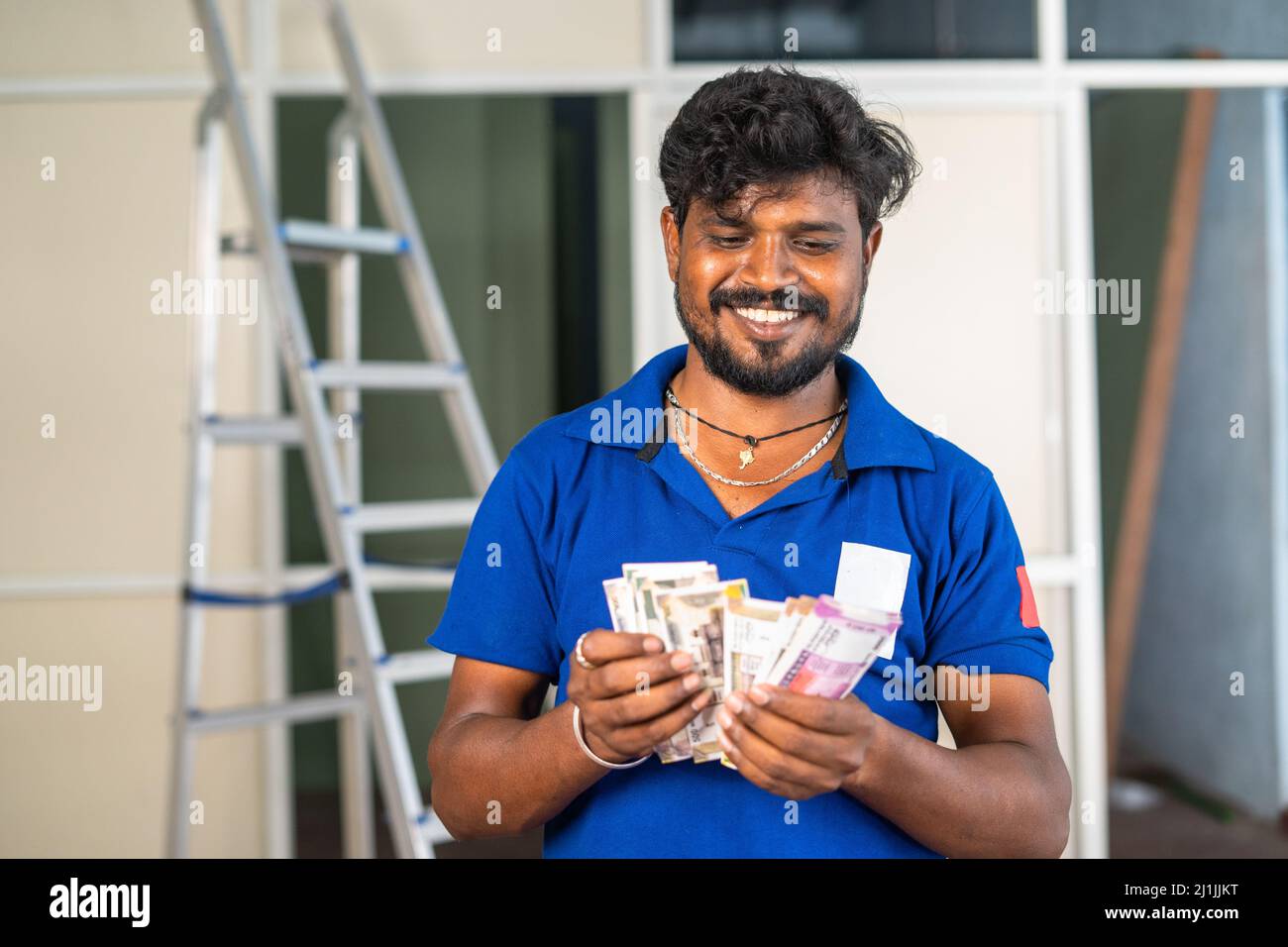 Smiling aluminium worker counting indian money at workplace - concept of banking support, earning or profit and maintenance or repair service. Stock Photo